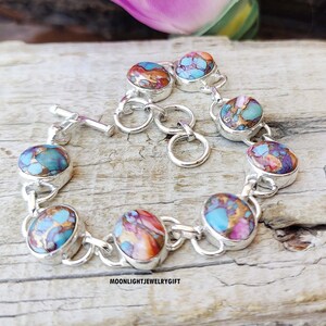 May include: A silver bracelet with turquoise and copper inlay stones. The bracelet has a toggle clasp and is made of sterling silver.