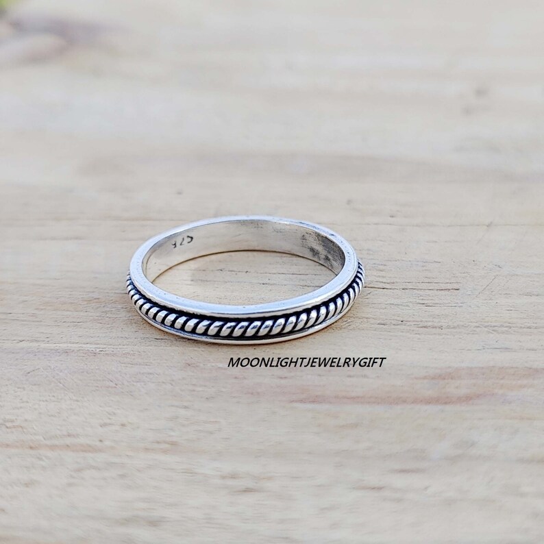 May include: A silver ring with a rope-like design around the band.