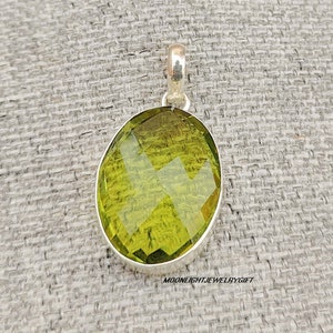 May include: A silver pendant featuring a large, faceted, oval-shaped green gemstone.
