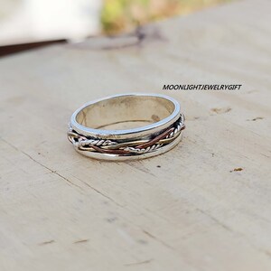 Pu&ograve; includere: Un anello a fascia d'argento con un design intrecciato con accenti in rame e oro.