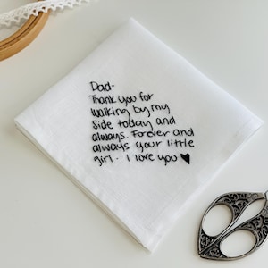 K&ouml;nnte beinhalten: Ein wei&szlig;es quadratisches Taschentuch mit schwarzem gesticktem Text: Dad- Thank you for walking by my side today and always. Forever and always your little girl. I love you, gefolgt von einem kleinen schwarzen gestickten Herzsymbol.
