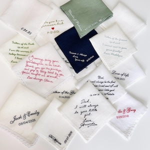 Puede incluir: Una colección de pañuelos de tela cuadrados en blanco, azul marino y verde salvia. Cada pieza presenta bordados personalizados con nombres, fechas y mensajes estilo manuscrito como 'Dad, I will always be your little girl.'
