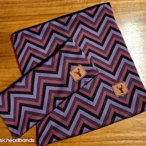Könnte beinhalten: Zwei gewebte Stirnbänder in Lila und Schwarz mit Chevron-Muster und einem braunen Leder-Patch mit einer Hirsch-Silhouette.