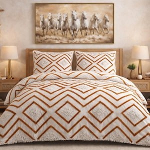 以下が含まれることがあります： 白と錆色の幾何学模様の掛け布団と枕のセットが特徴のベッドがある寝室のシーン。部屋には木製のベッドサイドテーブル、ランプ、走る白馬の絵画が含まれています。