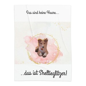 Puede incluir: Un lindo perro Sheltie con pelaje marrón y blanco está sentado en un círculo de acuarela rosa con brillo dorado. El texto "Das sind keine Haare... das ist Sheltieglitzer!" está escrito debajo del perro.
