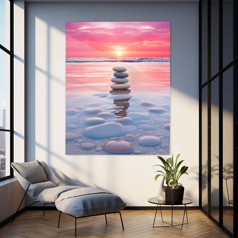 Puede incluir: Una pila de piedras lisas, grises y blancas, equilibradas unas sobre otras en aguas poco profundas. El agua es de color azul claro y el fondo es un cielo de puesta de sol rosa y naranja.