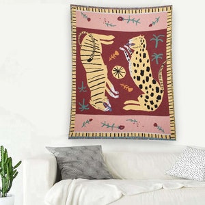 May include: A tapestry featuring a red background with two stylized animals, a tiger and a leopard, in yellow and brown. The tapestry has a pink and yellow border with floral and leaf designs.
