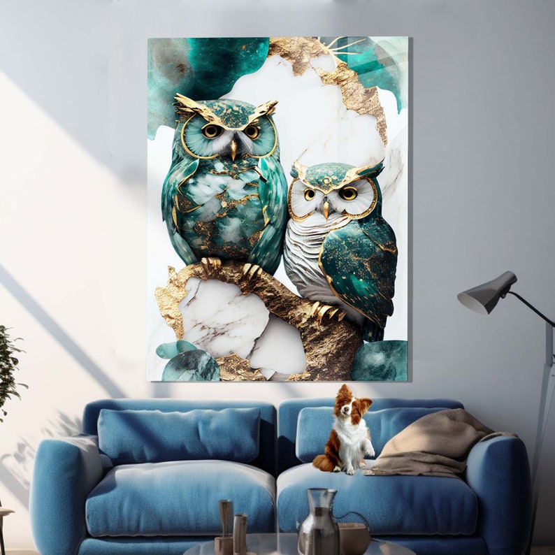 May include: Two owls with gold accents perched on a branch with a marble and gold background. The owls are green and blue with gold accents. The background is a mix of white marble and gold.