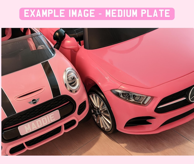 May include: Two pink toy cars are parked next to each other. One is a Mini Cooper with black racing stripes and a license plate that reads "MADDIE". The other is a Mercedes-Benz. The image has the text "EXAMPLE IMAGE - MEDIUM PLATE" at the top.