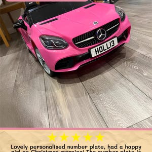 May include: A bright pink toy car with the text "HOLLI3" on the license plate. The car has a black grill and headlights. The image also includes the text "Medium Plate Example".