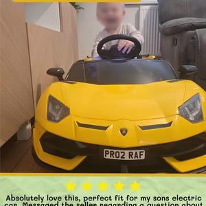 May include: A bright yellow electric toy car with black accents, featuring a steering wheel and a license plate that reads "PRO2 RAF". The car has a sleek, modern design, suitable for children.