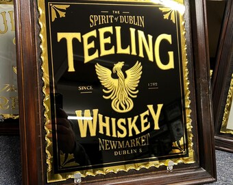 Könnte beinhalten: Ein gerahmter Spiegel mit schwarzem Hintergrund und goldenen Buchstaben. Der Text lautet "The Spirit of Dublin Teeling Whiskey Since 1789 Newmarket Dublin 8". Ein goldener Phönix befindet sich in der Mitte des Spiegels.