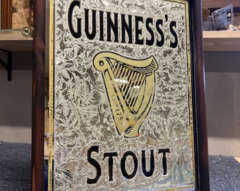 Könnte beinhalten: Ein Vintage-Guinness-Stout-Spiegel mit goldenem Rahmen. Der Spiegel hat einen silbernen Hintergrund mit einer goldenen Harfe und dem Text "GUINNESS'S ESTD 1778 STOUT".