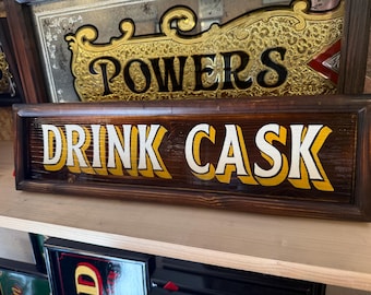 Drink cask   , traditionally hand lettered wooden pub/bar/mancave sign .