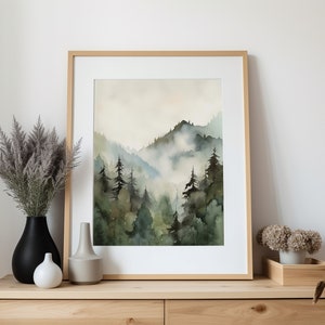 Pu&ograve; includere: Un dipinto ad acquerello incorniciato che rappresenta una scena di foresta nebbiosa con alberi verdi e montagne sullo sfondo.