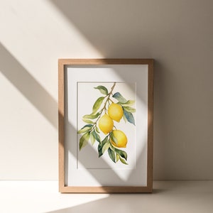 Op de afbeelding: Een ingelijst aquarel schilderij van een citroen tak met drie citroenen. De citroenen zijn geel en de bladeren zijn groen. Het schilderij is in een licht houten lijst.