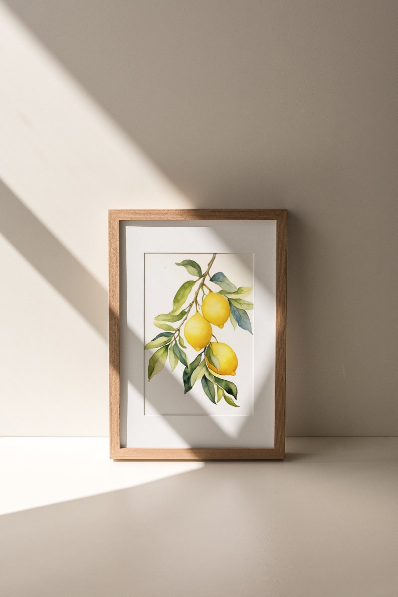 Op de afbeelding: Een ingelijst aquarel schilderij van een citroen tak met drie citroenen. De citroenen zijn geel en de bladeren zijn groen. Het schilderij is in een licht houten lijst.