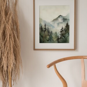Pu&ograve; includere: Un dipinto ad acquerello incorniciato che rappresenta una scena di foresta nebbiosa con alberi verdi e montagne. Il dipinto &egrave; in una cornice di legno chiaro ed &egrave; appeso a una parete bianca.