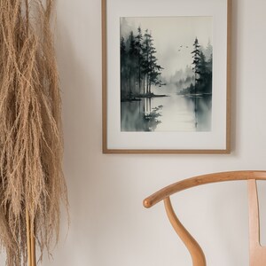 May include: A framed watercolor painting of a misty forest scene with a lake in the foreground. The trees are dark green and the water is a light blue. The painting is in a light wood frame.