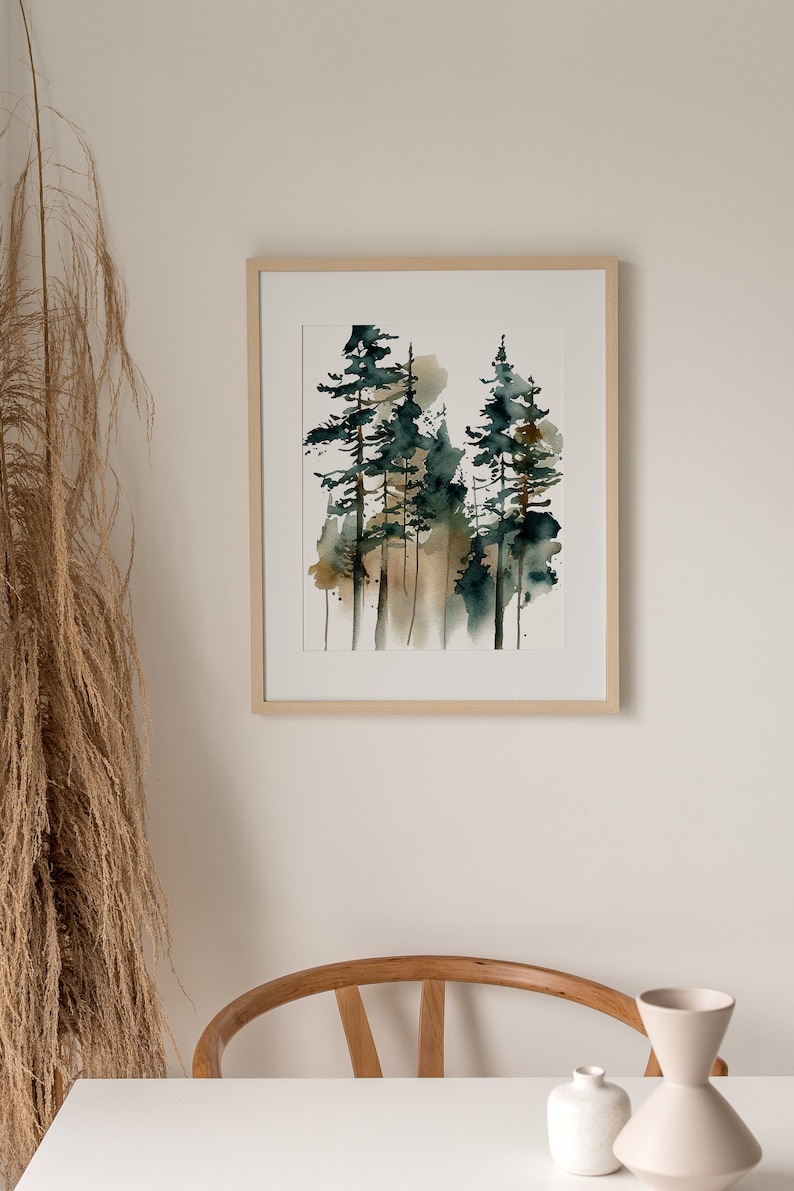 May include: Watercolor painting of a forest scene with tall evergreen trees in shades of green and brown. The artwork is framed in a light wood frame and displayed on a white wall. The painting evokes a sense of nature and tranquility.