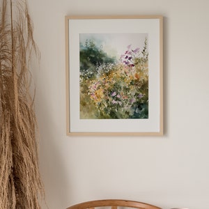 May include: A framed watercolor painting of a field of wildflowers in shades of purple, yellow, and green. The painting is set against a light background.