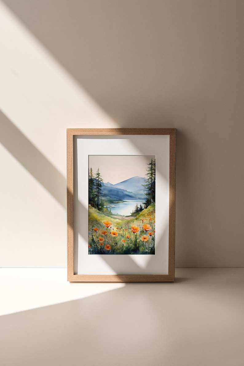 Puede incluir: Pintura acuarela enmarcada de un paisaje con un lago, monta&ntilde;as y un campo de amapolas naranjas.