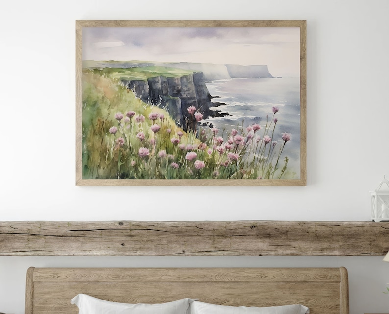 K&ouml;nnte beinhalten: Aquarellgem&auml;lde einer Klippe, die &uuml;ber einem Gew&auml;sser thront. Die Klippe ist gr&uuml;n und braun mit einer felsigen Textur. Das Wasser ist blau und hat wei&szlig;e Wellen. Im Vordergrund befinden sich rosa Blumen.