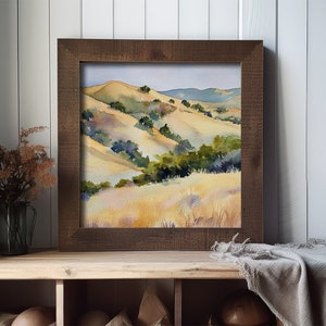 May include: Watercolor painting of rolling hills with green trees and yellow grass. The painting is framed in a dark brown wood frame.