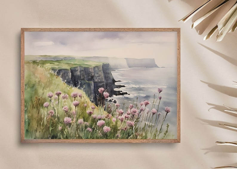 K&ouml;nnte beinhalten: Aquarellmalerei einer K&uuml;stenlandschaft mit dramatischen Klippen und einem Meer im Hintergrund. Im Vordergrund befindet sich ein Feld mit rosa Wildblumen.