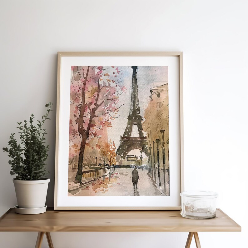 Puede incluir: Pintura acuarela de la Torre Eiffel en Par&iacute;s, Francia. La torre se representa en el fondo con una calle en primer plano. Una persona camina por la calle. Los &aacute;rboles est&aacute;n en flor con flores rosas.