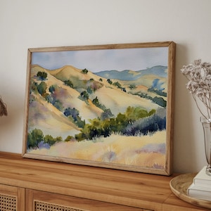 May include: Watercolor painting of a landscape with rolling hills, green trees, and a blue sky. The hills are painted in shades of yellow, brown, and green. The trees are painted in shades of green and blue. The sky is painted in shades of blue and white.