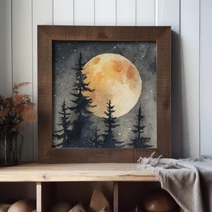 May include: Watercolor painting of a full moon over a forest of silhouetted pine trees. The artwork is framed in a dark brown wooden frame. The moon is a warm yellow color, and the sky is a dark gray with small white stars.