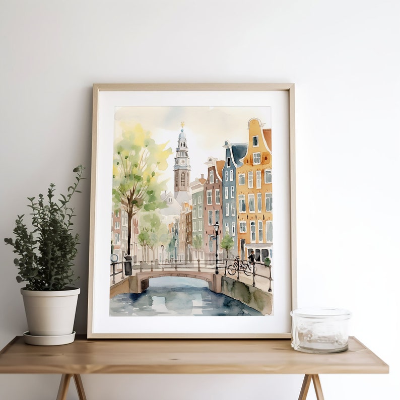 May include: Watercolor painting of a canal scene in Amsterdam, Netherlands. The painting features a bridge over a canal with colorful buildings lining the sides. There is a church steeple in the background.