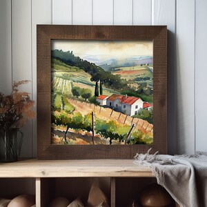 May include: A framed watercolor painting of a vineyard landscape. The artwork depicts rolling hills, rows of grapevines, and a small house with a red roof. The frame is made of dark brown wood, and the overall scene evokes a sense of tranquility and rural beauty.