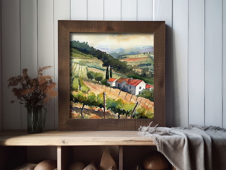 May include: A framed watercolor painting of a vineyard landscape. The artwork depicts rolling hills, rows of grapevines, and a small house with a red roof. The frame is made of dark brown wood, and the overall scene evokes a sense of tranquility and rural beauty.