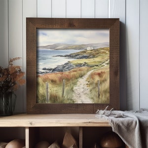 May include: A framed watercolour painting of a coastal scene with a white house on a hill overlooking a rocky beach and a path leading to it.