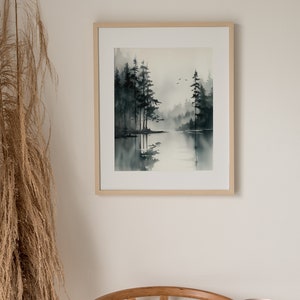 May include: A framed watercolor painting of a misty forest scene with a lake in the foreground. The trees are dark green and the water is a light blue. The painting is in a simple wooden frame.