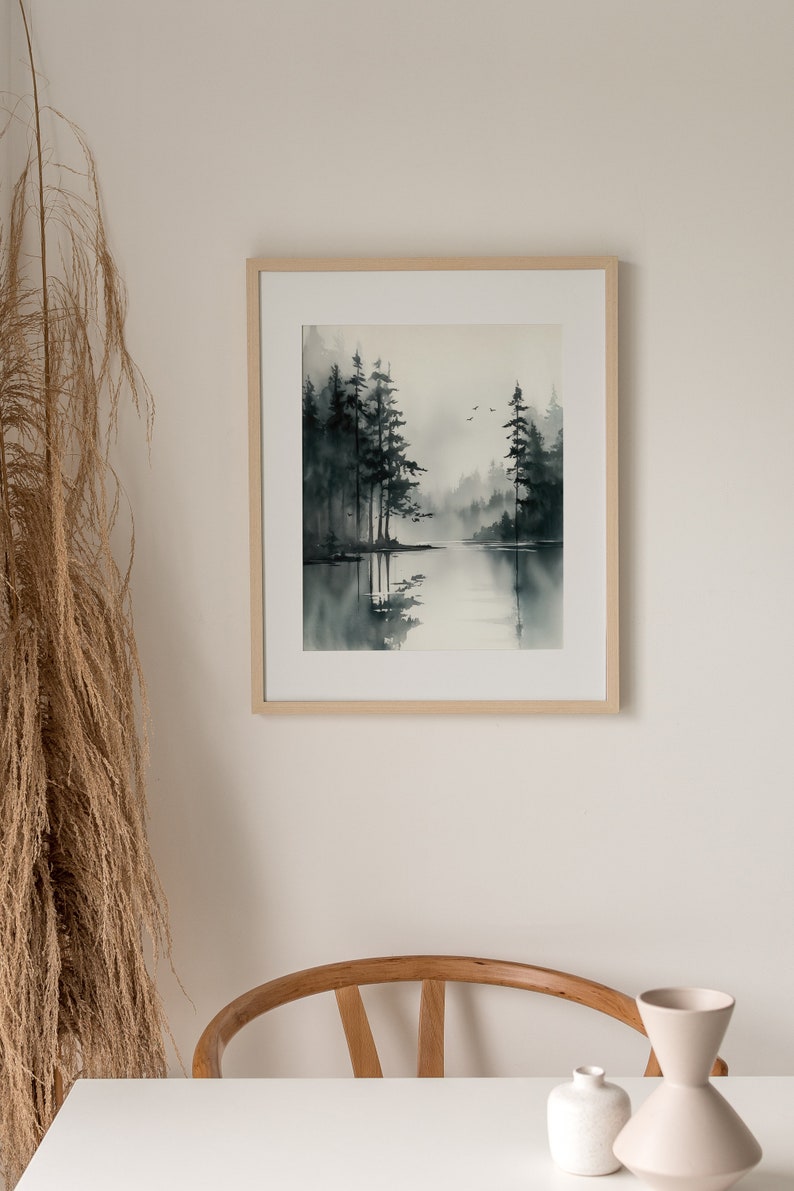 May include: A framed watercolor painting of a misty forest scene with a lake in the foreground. The trees are dark green and the water is a light blue. The painting is in a simple wooden frame.