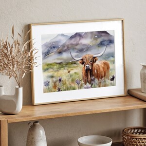 May include: A watercolor painting of a Highland cow standing in a field of wildflowers. The cow is brown and white with long horns. The background is a misty mountain landscape.