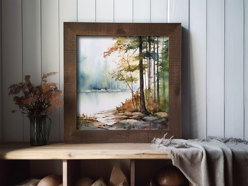 May include: A framed watercolor painting of a forest scene with a lake in the foreground. The trees are a mix of green and brown, and the water is a light blue. The painting is in a rustic wooden frame.