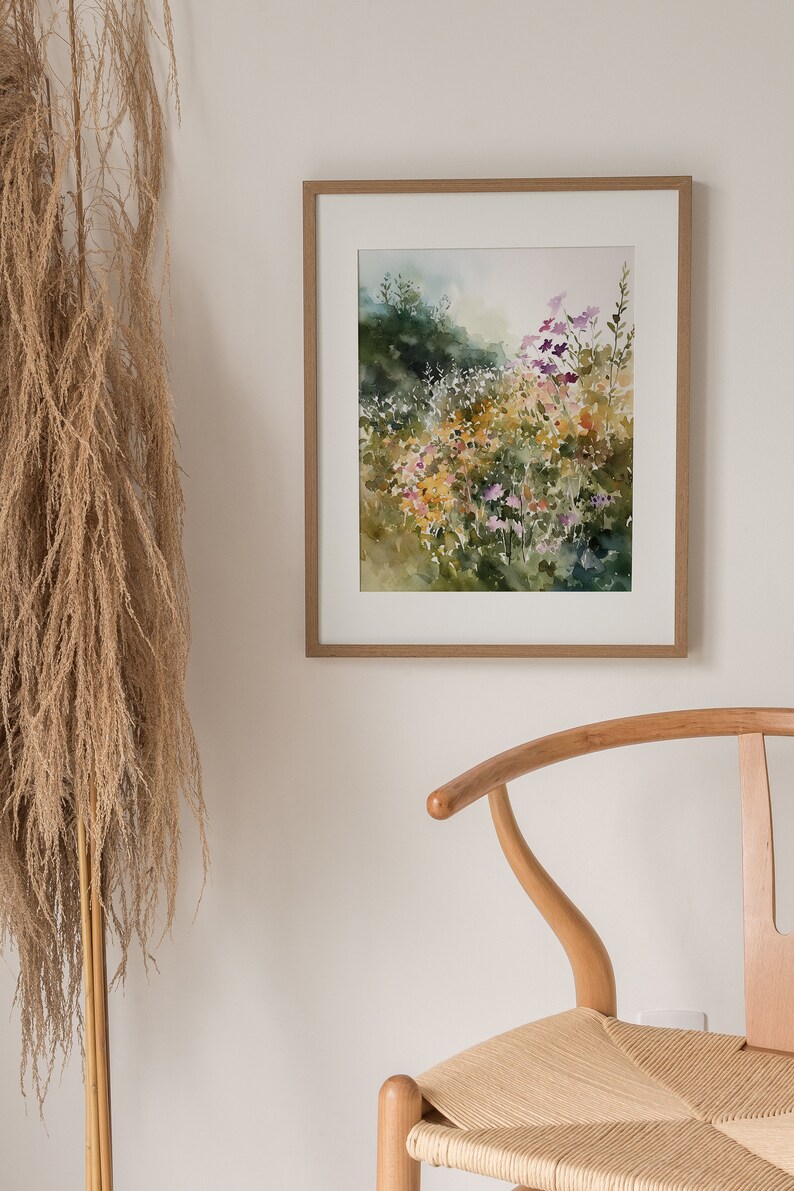 May include: A framed watercolor painting of a field of wildflowers in shades of purple, yellow, and green. The painting is set against a white wall with a wooden chair in the foreground.