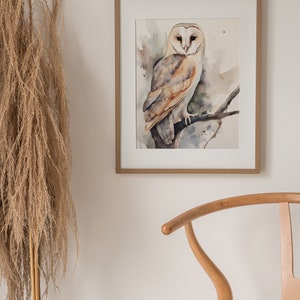 May include: A watercolor painting of a barn owl perched on a branch. The owl is white with brown markings and has large, yellow eyes. The background is a soft, watercolor wash of greens and browns.