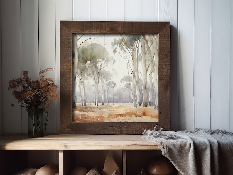 May include: A framed watercolour painting of a woodland scene with tall trees and a light brown background. The frame is a dark brown wood.