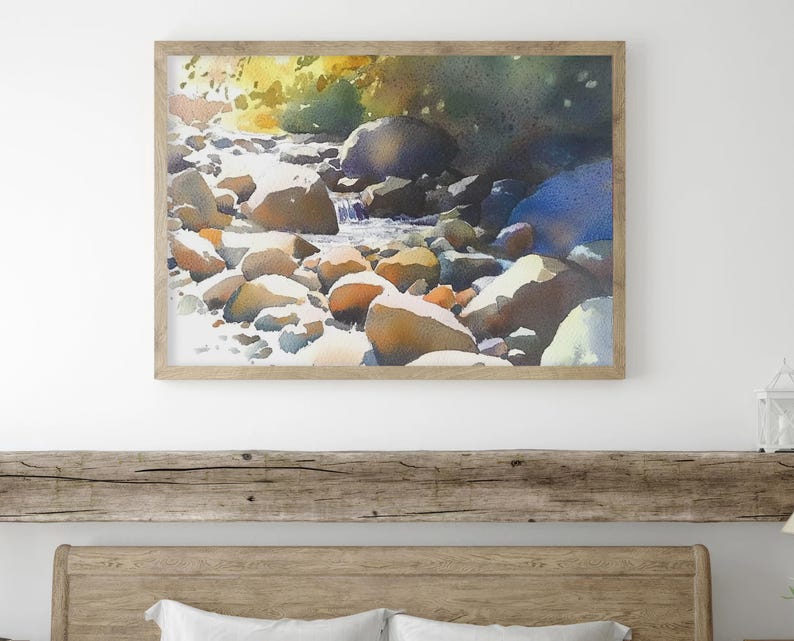May include: Watercolor painting of a stream flowing over smooth, rounded rocks. The water is a light blue, and the rocks are a variety of colors, including brown, gray, and white. The background is a blur of green and blue, suggesting trees and foliage.