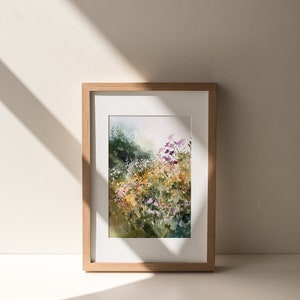 May include: A framed watercolor painting of a field of wildflowers in shades of purple, pink, yellow, and white. The flowers are set against a background of green foliage and a hazy sky.