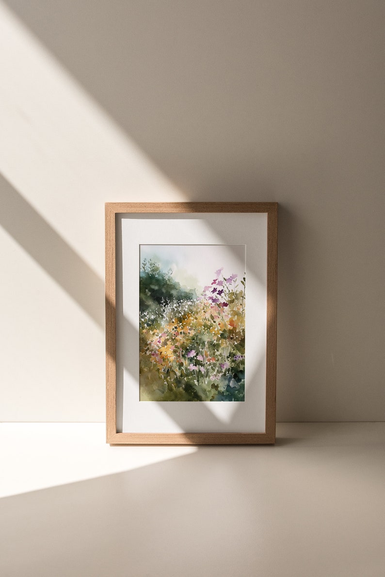 May include: A framed watercolor painting of a field of wildflowers in shades of purple, pink, yellow, and white. The flowers are set against a background of green foliage and a hazy sky.