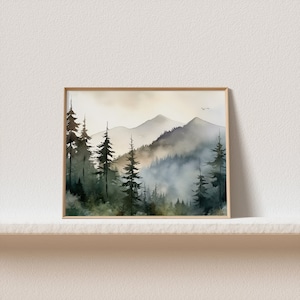 May include: A watercolor painting of a misty mountain landscape with a forest of evergreen trees in the foreground. The sky is a soft, muted yellow, and the mountains are a hazy blue-gray. The painting is framed in a simple, light wood frame.