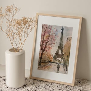 Puede incluir: Una pintura de acuarela enmarcada de la Torre Eiffel en Par&iacute;s, Francia. La pintura representa la torre con un cerezo en flor rosa y blanco en primer plano. Una sola persona camina en la distancia.