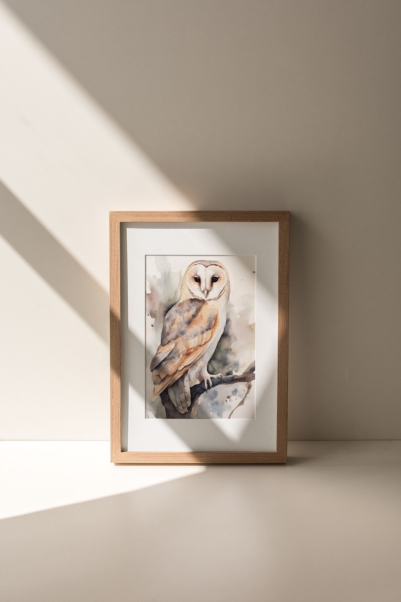 May include: A framed watercolor painting of a barn owl perched on a branch. The owl has white feathers with brown markings and yellow eyes. The background is a soft watercolor wash of brown and blue.