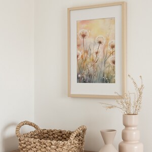 May include: A framed watercolor painting of dandelion flowers in shades of white, yellow, and brown, hanging on a white wall above a wooden dresser with a woven basket and two ceramic vases.